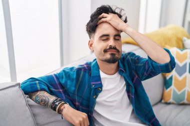 Evdeki kanepede oturan İspanyol genç adam.