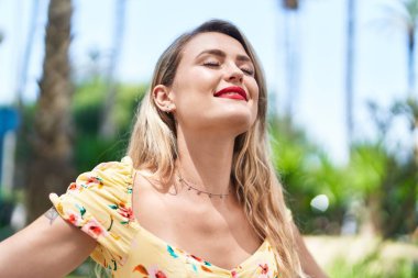 Young beautiful hispanic woman breathing with closed eyes at park