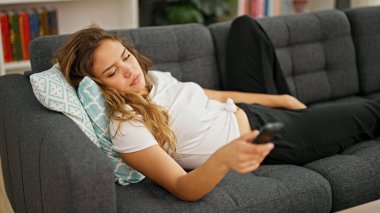 Evdeki kanepede uzanmış televizyon izleyen güzel İspanyol kadın.