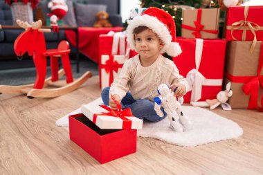 Sevimli İspanyol çocuk evde Noel ağacının yanında yerde oturan oyuncak kutusunu açıyor.
