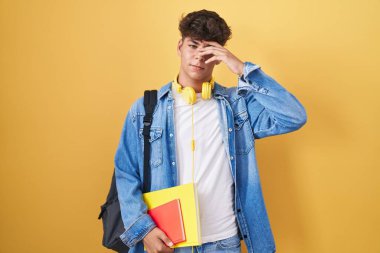 İspanyol ergen öğrenci çantası takıyor ve elinde kitap tutuyor. Alnındaki sorun yüzünden endişeli ve stresli. Kriz için endişeli. 