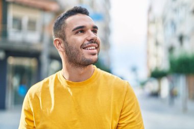 Young hispanic man smiling confident looking to the sky at street