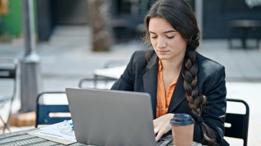 Genç, güzel İspanyol iş kadını. Kahve dükkanının terasında dizüstü bilgisayar kullanıyor.
