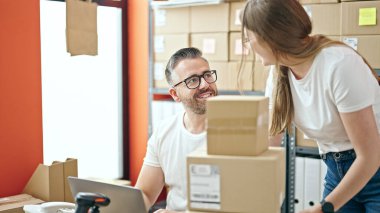 Genç kadın ve erkek ofiste dizüstü bilgisayarla ekommerce üzerinde çalışıyorlar.