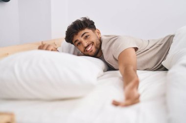Young arab man smiling confident lying on bed at bedroom