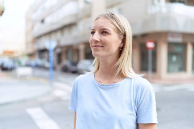 Young blonde woman smiling confident looking to the side at street