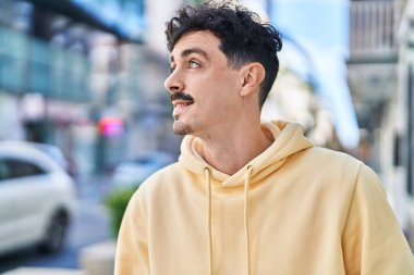 Young caucasian man smiling confident looking to the side at street