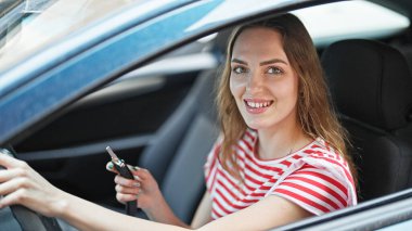 Genç sarışın kadın gülümsüyor. Elinde yeni arabanın anahtarı var.