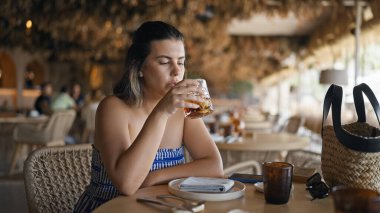 Genç İspanyol kadın restoranda bir bardak vermut içiyor.