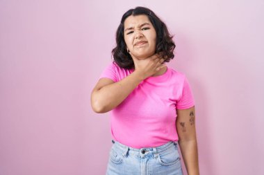 Pembe arka planda dikilen genç İspanyol kadın bıçakla boğazını kesiyor, saldırganlığı şiddetle tehdit ediyor. 