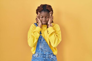 Sarı arka planda el üstünde duran Afrikalı kadın, baş ağrısı, stres yüzünden. migren ağrısı. 