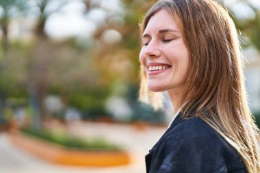 Young blonde woman smiling confident looking to the side at park