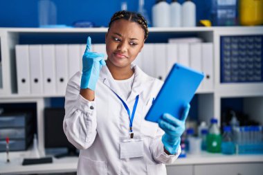 Örgü ören Afrikalı Amerikalı bir kadın bilim adamı laboratuarında çalışıyor. Tabletle video görüşmesi yapıyor. Bir fikir veya soruyla gülümsüyor. 