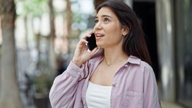 Genç ve güzel İspanyol bir kadın akıllı telefonda konuşuyor. Sokakta ciddi bir ifadeyle.