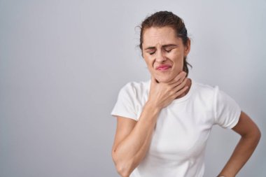 Güzel esmer kadın izole edilmiş arka planda duruyor. Acı veren boynuna dokunuyor. Grip, mantar ve enfeksiyon yüzünden boğazı ağrıyor. 