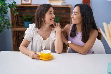 Two women mother and daughter drinking coffee at home