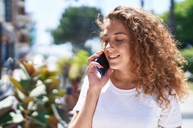 Genç, güzel İspanyol kadın gülümsüyor. Parktaki akıllı telefondan konuşuyor.