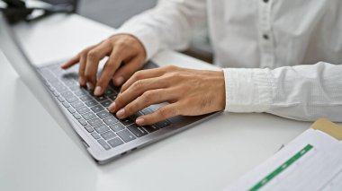 İspanyol adam işini yapıyor, elleri dizüstü bilgisayarın üzerinde uçuyor, iş dünyasının kalbinde yazı yazıyor, ofis kaosu; başarı odada yankılanıyor
