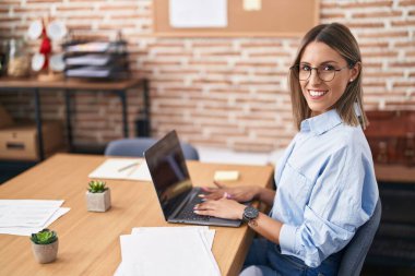 Young beautiful hispanic woman business worker smiling confident using laptop at office