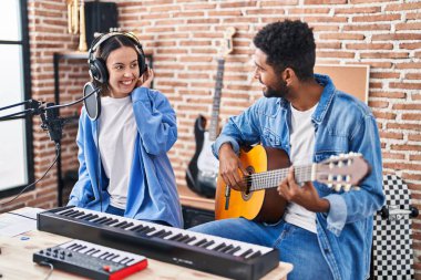 Klasik gitar çalan erkek ve kadın müzisyenler müzik stüdyosunda şarkı söylüyorlar.