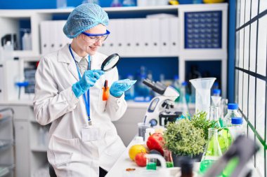 Genç sarışın bilim adamı laboratuarda büyüteçle örnek arıyor.