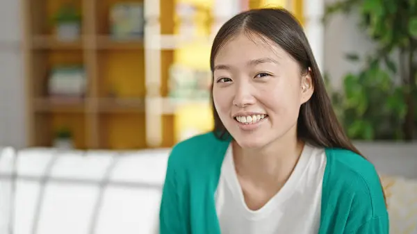 Young chinese woman smiling confident sitting on sofa at home