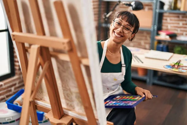 Sanat stüdyosunda kendine güvenen güzel İspanyol kadın sanatçı gülümsüyor.