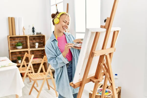 Young caucasian woman artist listening to music drawing at art studio