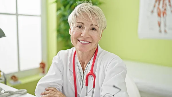 Middle Age Blonde Woman Doctor Smiling Confident Sitting Arms Crossed — Stock Photo, Image