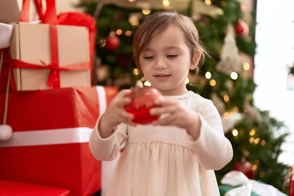 愛らしい女の子保持ボール装飾スタンディングによってクリスマスツリーに家 — ストック写真