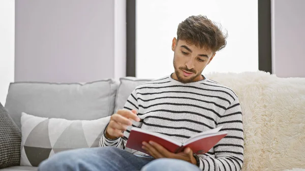 Young Arab Man Reading Book Sitting Sofa Home — Stock Photo, Image