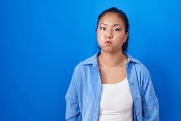Mujer Joven Asiática Pie Sobre Fondo Azul Hinchando Mejillas Con —  Fotos de Stock