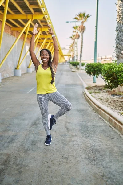 Spor kıyafetleri giyen Afrikalı Amerikalı kadın sokakta yoga egzersizi yapıyor.