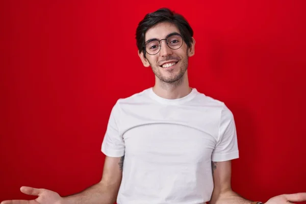 Junger Hispanischer Mann Der Vor Rotem Hintergrund Steht Lächelt Fröhlich — Stockfoto