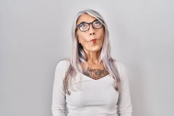 白い背景の上に立っている灰色の髪を持つ中年の女性は クレイジーでコミカルなジェスチャーで魚の顔を作ります おかしい表現 — ストック写真