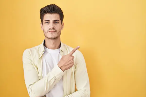 Mladý Hispánec Stojící Nad Žlutým Pozadím Ukazuje Ukazováčkem Stranu Reklamou — Stock fotografie
