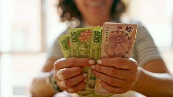 stock image Middle age hispanic woman counting argentina 100 and 500 pesos banknotes at home