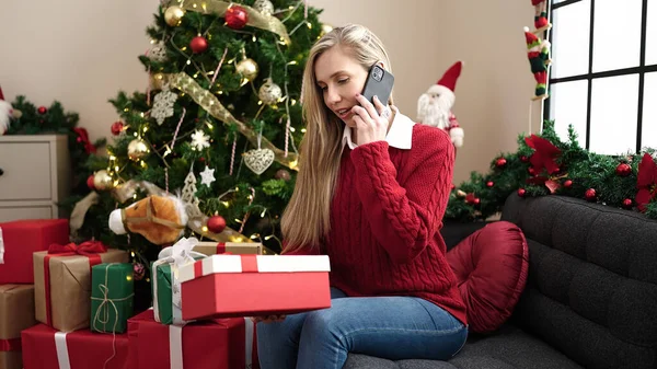 Νεαρή Ξανθιά Γυναίκα Που Μιλάει Στο Smartphone Κρατώντας Χριστουγεννιάτικο Δώρο — Φωτογραφία Αρχείου