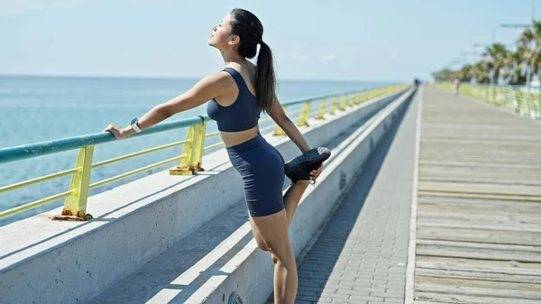 Young Beautiful Hispanic Woman Wearing Sportswear Stretching Legs Seaside — Stock Photo, Image