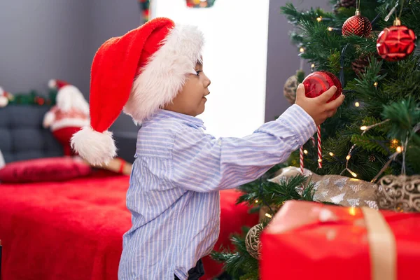 自宅でクリスマスツリーを飾る自信を持って微笑む愛らしいヒスパニックの幼児 — ストック写真