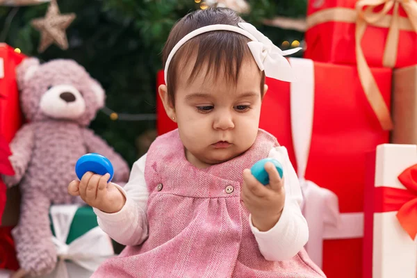 自宅でクリスマスツリーで床に座っているホップのおもちゃを保持する愛らしいヒスパニックの赤ちゃん — ストック写真