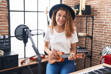 Genç, güzel, İspanyol bir müzisyen müzik stüdyosunda ukulele çalıyor.