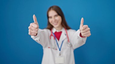 Genç İspanyol kadın doktor, izole edilmiş mavi arkaplanı onaylıyor.