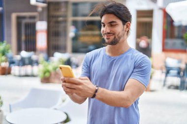Sokakta akıllı telefon kullanan, kendine güvenen genç bir İspanyol.