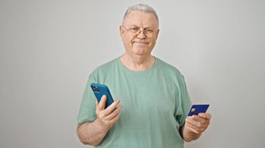 Orta yaşlı, beyaz saçlı, akıllı telefon ve kredi kartıyla alışveriş yapan bir adam.