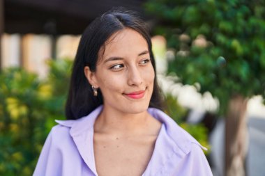Young beautiful hispanic woman smiling confident looking to the side at street