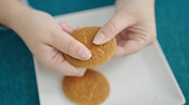 Genç İspanyol kadın yemek odasında kurabiye kırıyor.