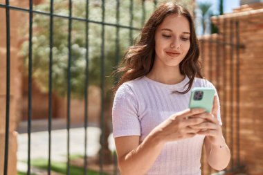 Sokakta akıllı telefon kullanan kendine güvenen genç bir kadın.