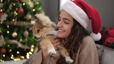 Köpeğiyle gülümseyen genç İspanyol kadın Noel 'i evde kutluyor.