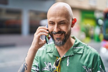 Genç kel adam gülümsüyor. Kendine güveni tam. Akıllı telefondan konuşuyor.